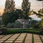 Mains d'un jardinier dans la terre près de plates-bandes négligées et d'une maison en arrière-plan