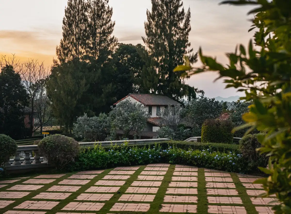 Mains d'un jardinier dans la terre près de plates-bandes négligées et d'une maison en arrière-plan