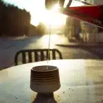 Personne buvant un verre d'eau le matin dans une cuisine baignée de lumière naturelle