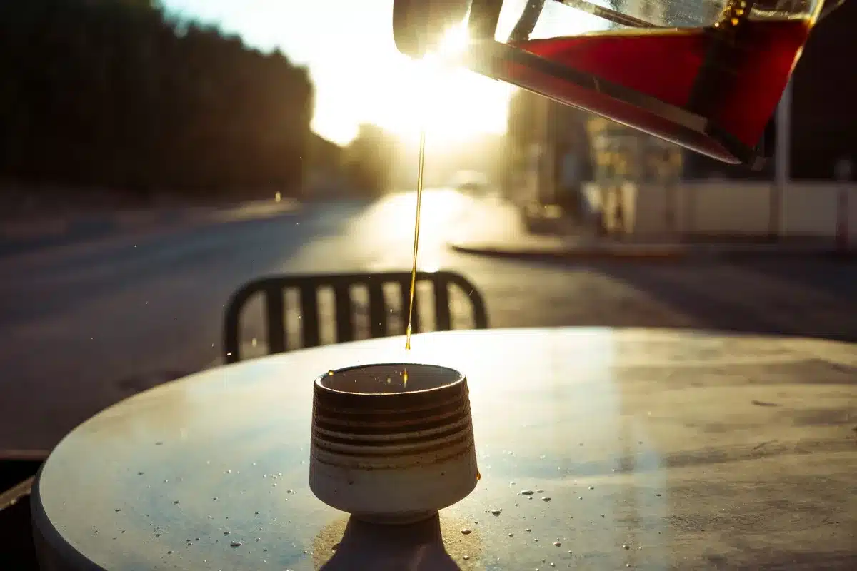 Personne buvant un verre d'eau le matin dans une cuisine baignée de lumière naturelle
