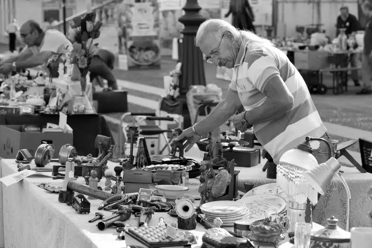 Visiteur explorant les étals d'un marché aux puces ou d'une brocante à la recherche de trésors