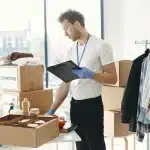 Mains triant des vêtements usés près de bacs de recyclage et de dons