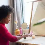 Mains anonymes ajustant un miroir sur une commode vintage en bois