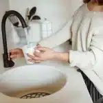 Une personne verse de l'eau dans un verre à la cuisine