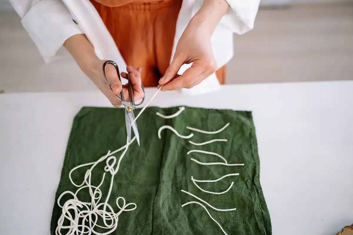 Mains assemblant des chemins de table colorés sur une surface plane pour créer un tapis artisanal