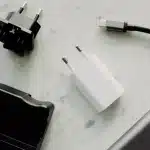 Mains d'une personne débranchant un chargeur de téléphone d'une prise murale