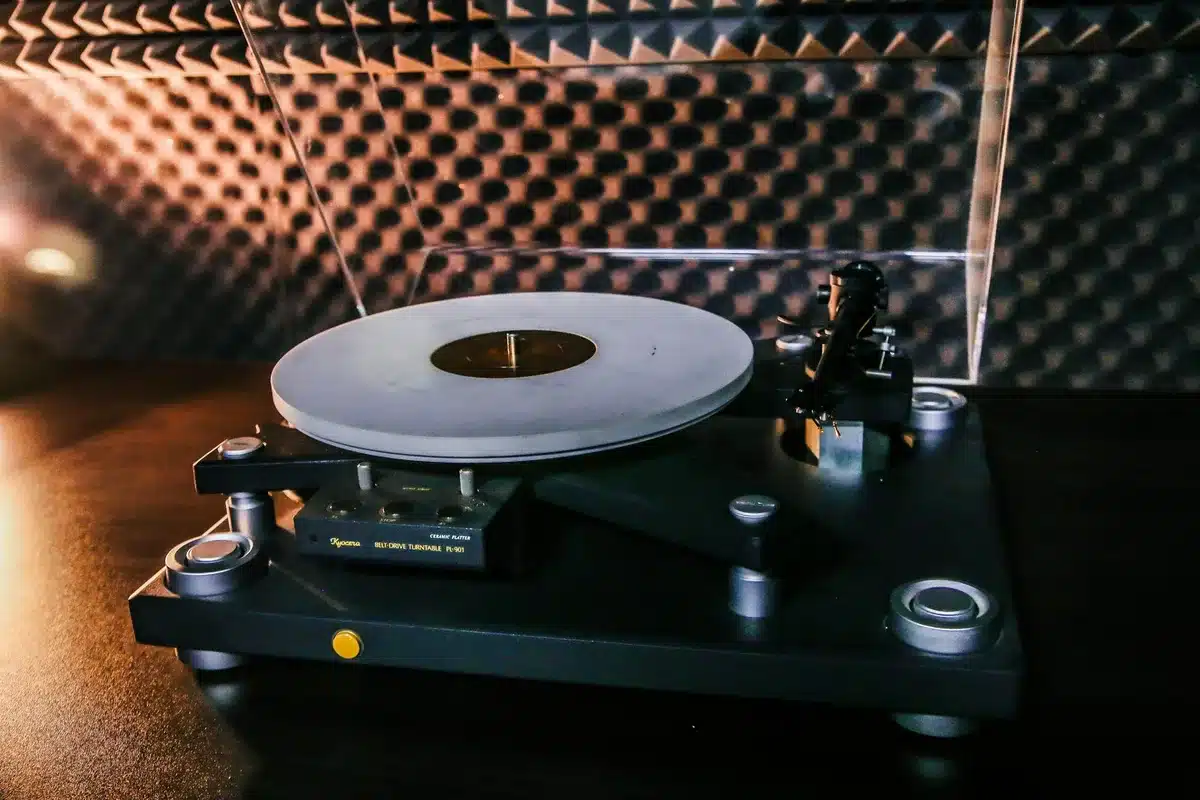 Main vinyl record being placé sur une platine tournante dans une lumière douce