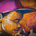 Mains appliquant un pochoir géométrique sur un mur avec un pinceau et de la peinture grise et bleue