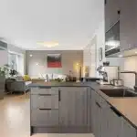 Intérieur d'un meuble sous-évier en plein jour, mains examinant un siphon et raccords