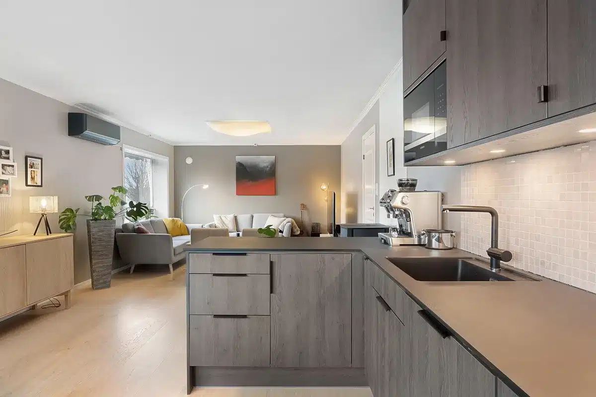 Intérieur d'un meuble sous-évier en plein jour, mains examinant un siphon et raccords