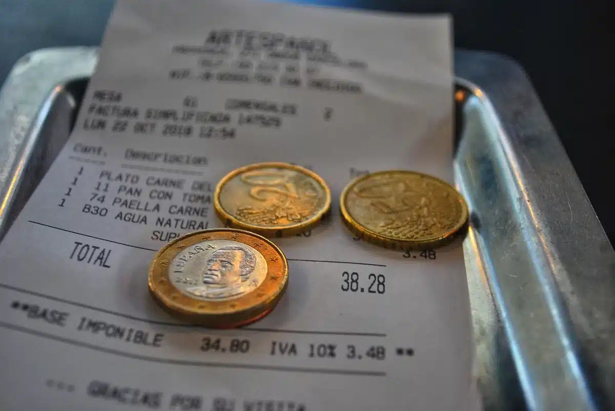 Mains tenant des tickets de caisse et un smartphone affichant une application de finances