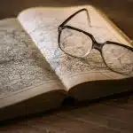 Main triant des documents anciens sur une table ensoleillée avec une loupe