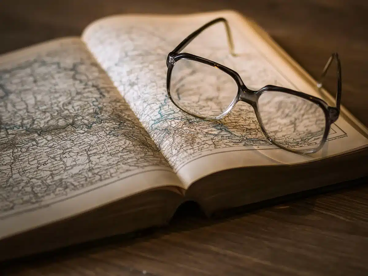 Main triant des documents anciens sur une table ensoleillée avec une loupe