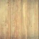 Main gantée appliquant une solution dans une fissure d'un parquet clair, chiffon et flacon à côté