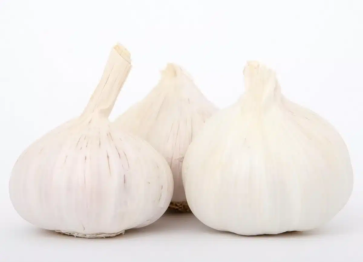 Patates douces, oignon et gousse d'ail posés sur un plan de travail